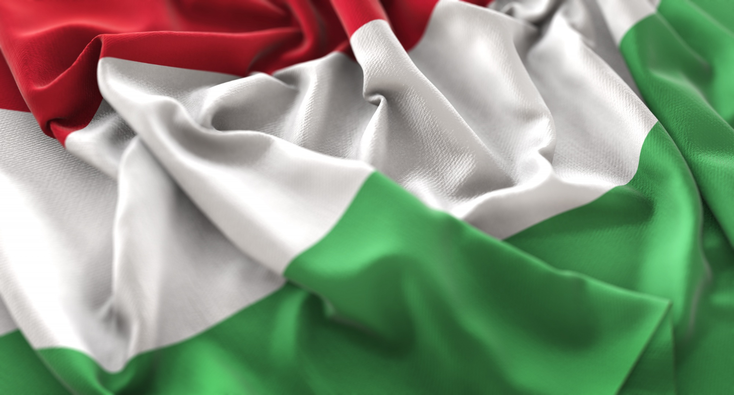 A close-up image of a fabric flag featuring horizontal stripes in three colors: red on top, white in the middle, and green on the bottom. The fabric appears soft and slightly wrinkled, creating a sense of movement and texture in the flag. The colors are vibrant and distinct, symbolizing the national identity of Hungary.