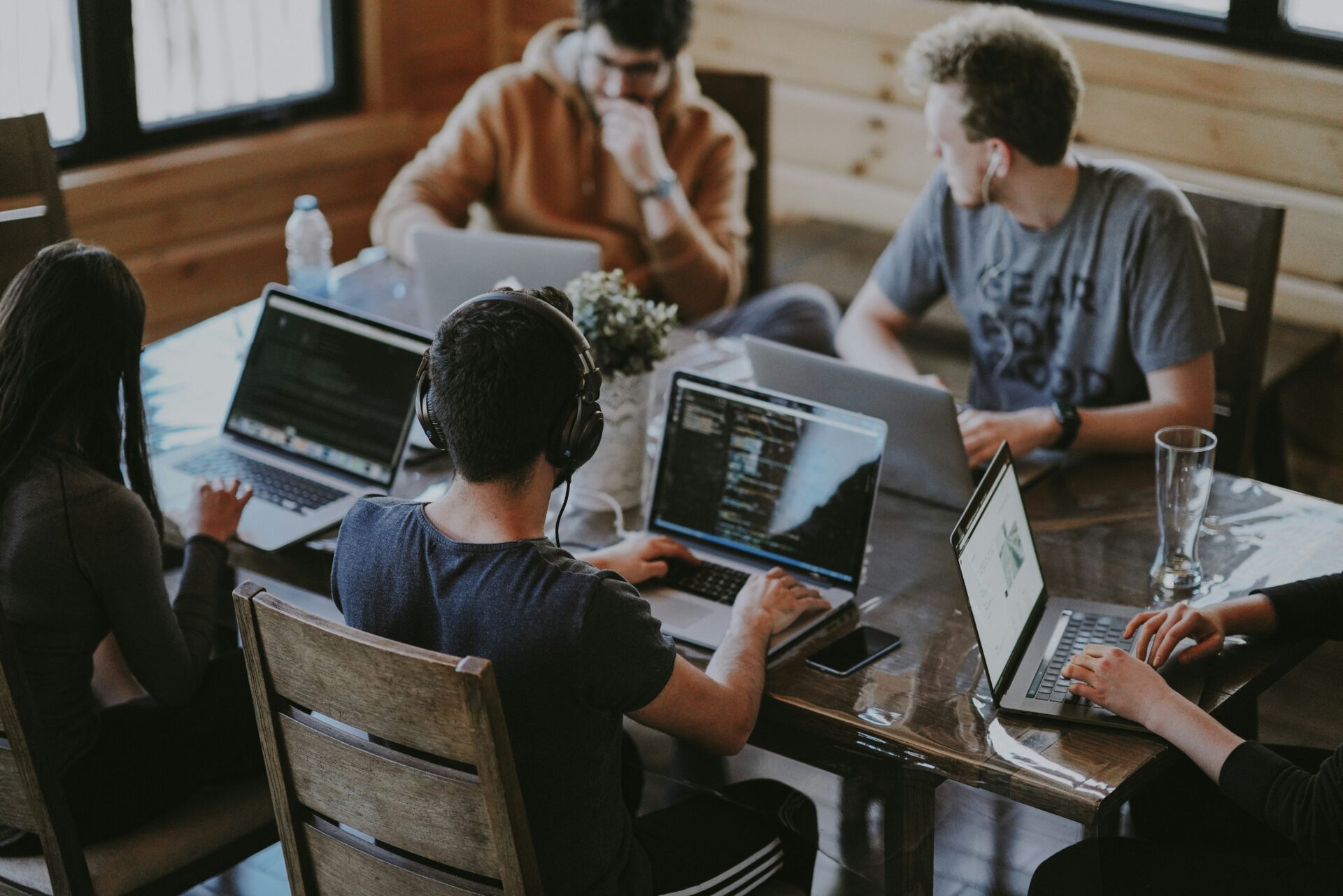 An image of number of employee working on the same table each is looking at his laptop