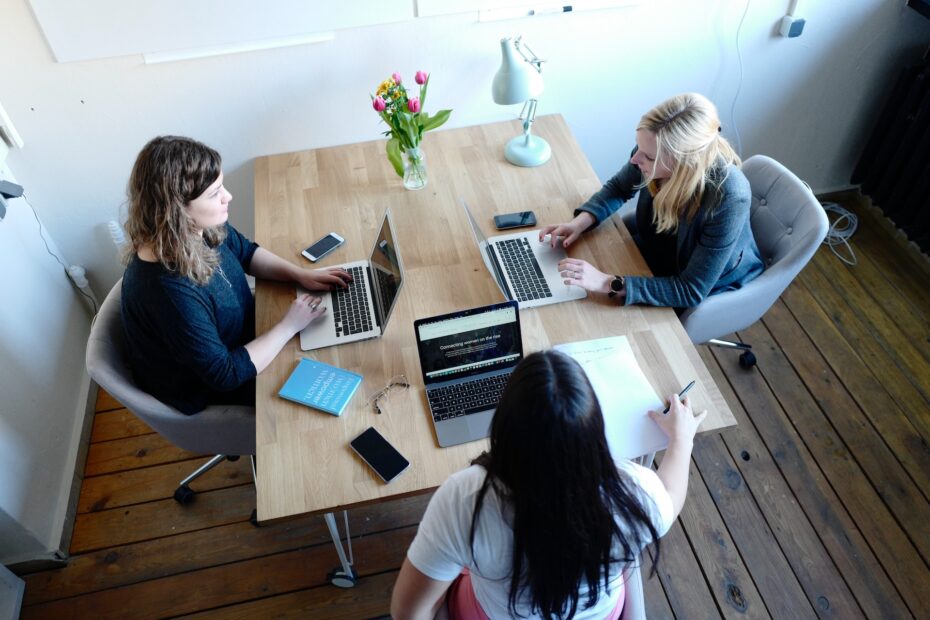 An image of three female employees sitting on the same table each one with her laptop