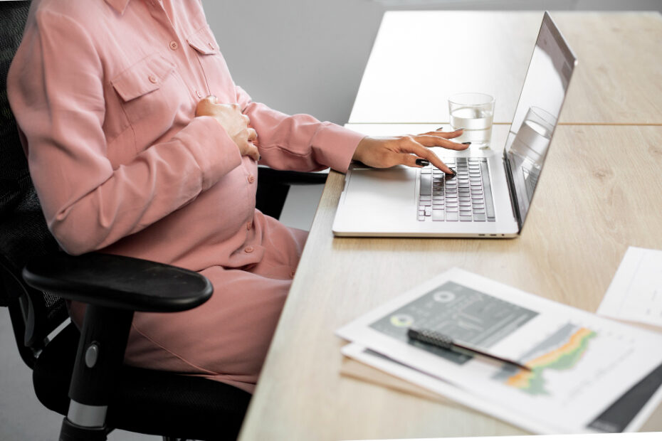 close up pregnant woman typing on her laptop in work