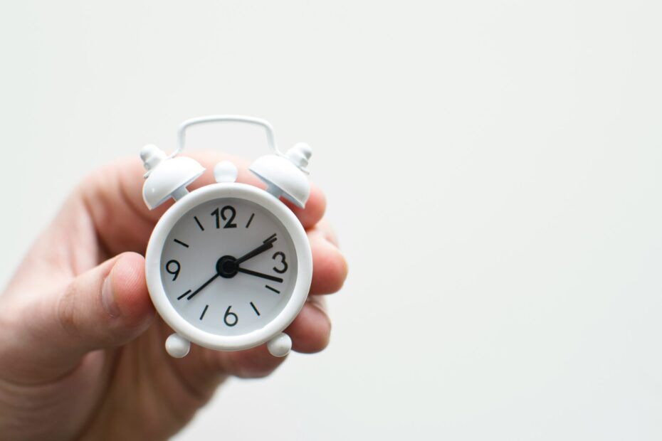 An image of a hand holding a small white clock