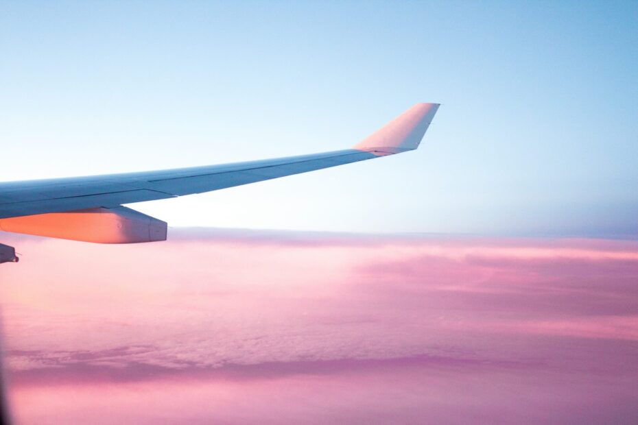 A picture of a plane flying through a sky filled with pink-hued clouds