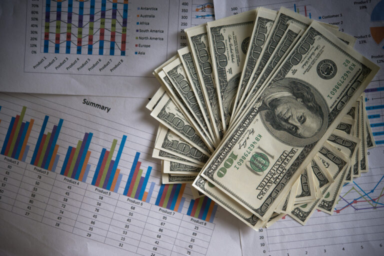 An image of some dollars put on the top of some statistics and reports