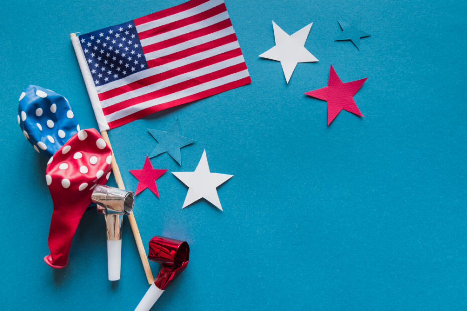 "Festive arrangement featuring a small American flag, colorful red and blue polka-dot balloons, party blowers, and red, white, and blue star-shaped decorations on a bright blue background."