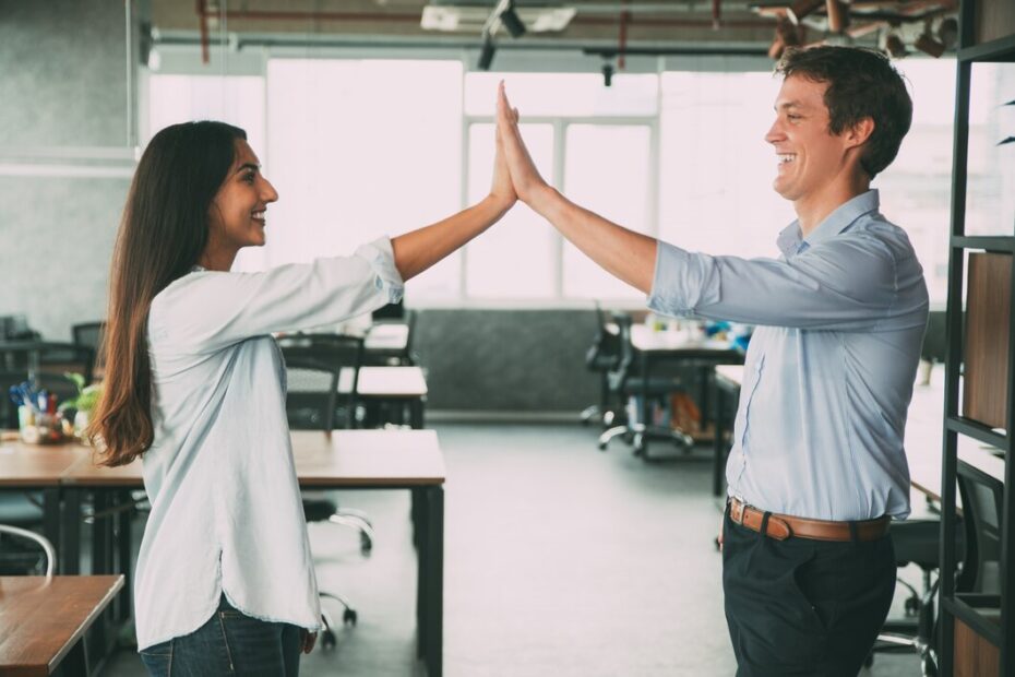 Two colleagues high-fiving in an office setting, celebrating with positivity and farewell quotes as one prepares to leave for new opportunities.