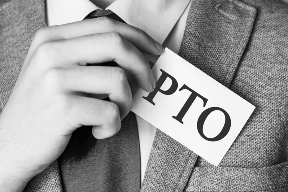 A black-and-white image of a professional in a suit holding a card with "PTO" written on it, symbolizing the concept of how PTO accrues in the workplace.