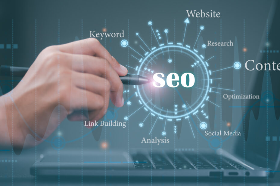 A digital representation of SEO (Search Engine Optimization) concepts, featuring a hand holding a pen pointing at the word "SEO" in a futuristic interface. Surrounding keywords such as "Website," "Content," "Keyword," "Research," "Optimization," "Social Media," "Link Building," and "Analysis" emphasize various aspects of SEO. A laptop in the background symbolizes the digital nature of SEO strategies.